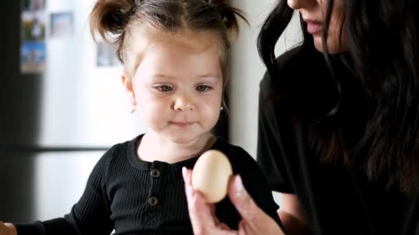 Küçük kız annesiyle mutfakta yumurta kırıyor. — Stok video