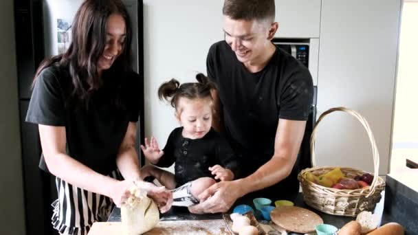 Pareja con hija pequeña preparando cupcakes en cocina moderna — Vídeos de Stock