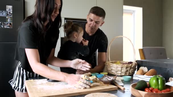 Pareja con hija pequeña preparando cupcakes en cocina moderna — Vídeo de stock