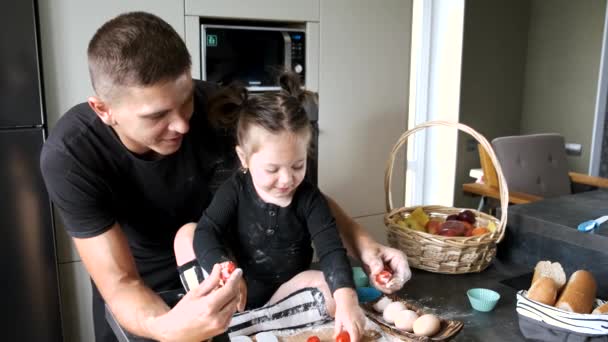 Vater und kleines Mädchen in schwarzen T-Shirts kochen in der Küche — Stockvideo