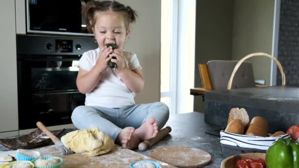 Niña en camiseta blanca sentada en la mesa en la cocina — Vídeos de Stock