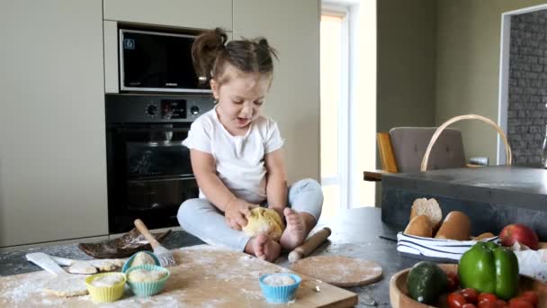 Niña en camiseta blanca sentada en la mesa en la cocina — Vídeo de stock