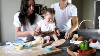 Aile üyeleri modern mutfakta hamur yoğuruyorlar.