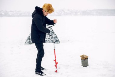 Kışın balık tutan yakışıklı bir adam.