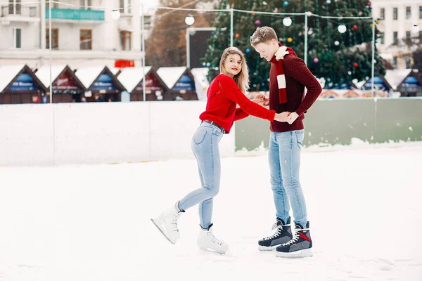 Cute para w czerwonych swetrach zabawy na arenie lodowej — Zdjęcie stockowe