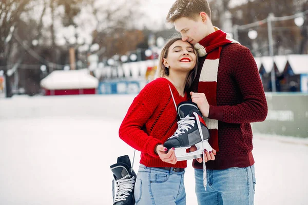Мила пара в червоних светрах розважається на льодовій арені — стокове фото