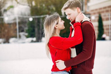 Kış şehrinde kırmızı kazaklar içinde sevimli ve sevgi dolu bir çift.