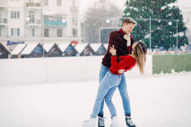 Kırmızı kazaklı şirin bir çift buz arenasında eğleniyor.