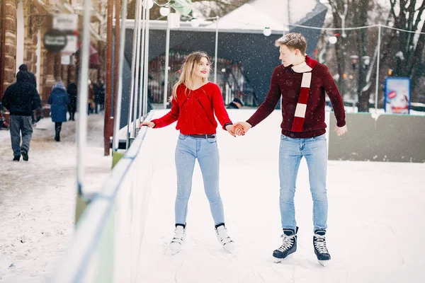 Cute para w czerwonych swetrach zabawy na arenie lodowej — Zdjęcie stockowe