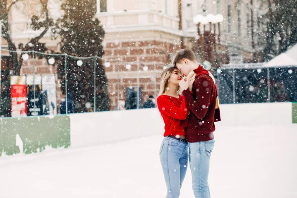 Aranyos és szerető pár egy piros pulóverben egy téli városban — Stock Fotó