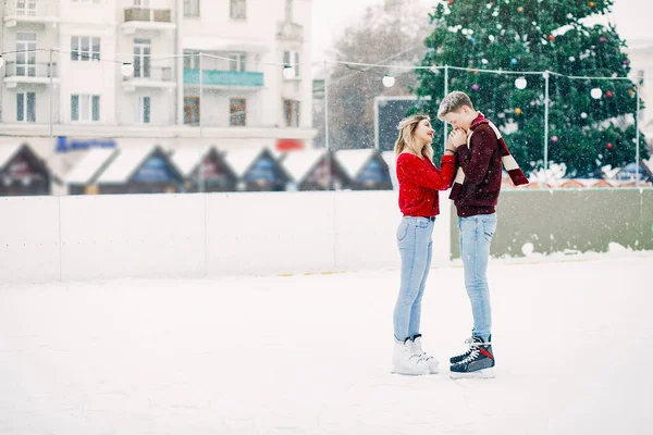 Söta par i röda tröjor som har kul på en isarena — Stockfoto