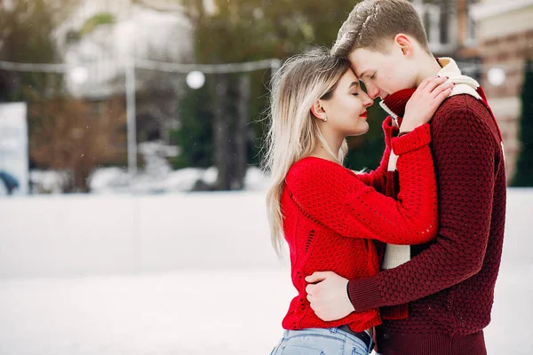 Linda y amorosa pareja en suéteres rojos en una ciudad de invierno — Foto de Stock