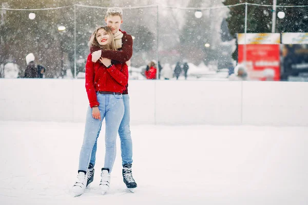 Cute para w czerwonych swetrach zabawy na arenie lodowej — Zdjęcie stockowe