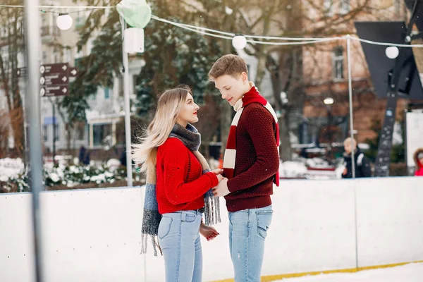 Söta par i röda tröjor som har kul på en isarena — Stockfoto