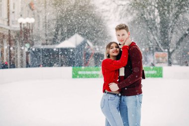 Kırmızı kazaklı şirin bir çift buz arenasında eğleniyor.