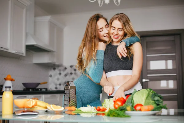 Dois esportes menina em uma cozinha com legumes — Fotografia de Stock