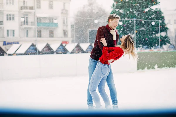 Cute para w czerwonych swetrach zabawy na arenie lodowej — Zdjęcie stockowe