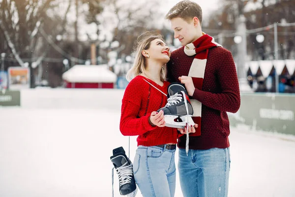 Cute couple in a red sweaters having fun in a ice arena — Stock Photo, Image