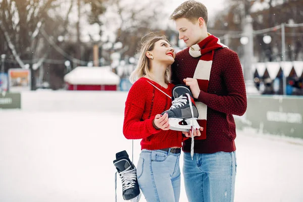 Cute para w czerwonych swetrach zabawy na arenie lodowej — Zdjęcie stockowe