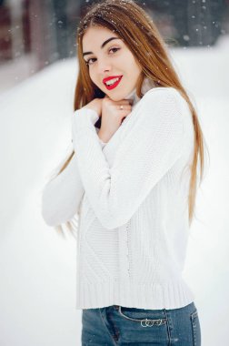 Kış parkında duran beyaz kazaklı genç kız.