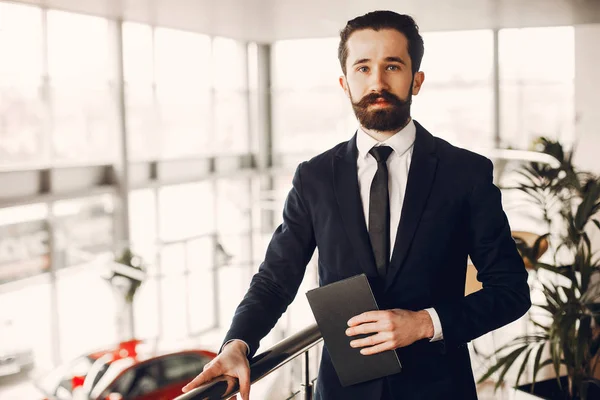 Hombre guapo y elegante en un salón de coches — Foto de Stock