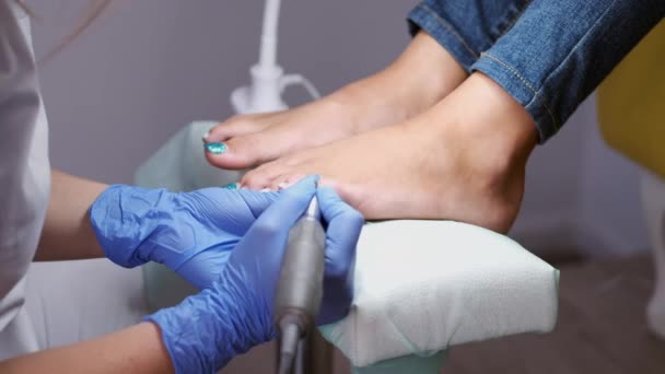 El técnico de uñas está puliendo clavos en los dedos de los pies por un cortador de pedicura — Vídeo de stock