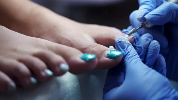Мастер по педикюру полирует ногти фрезой — стоковое видео
