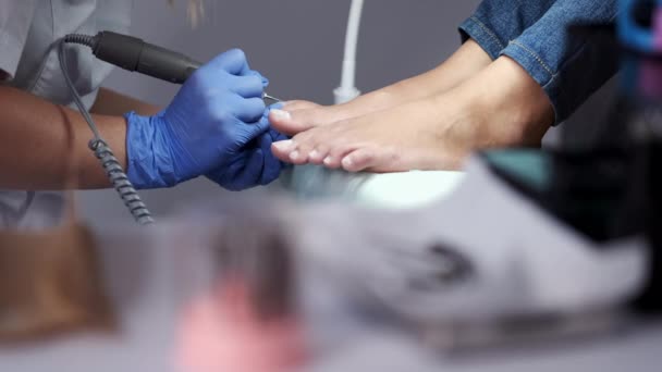 El técnico de uñas está puliendo clavos en los dedos de los pies por un cortador de pedicura — Vídeo de stock