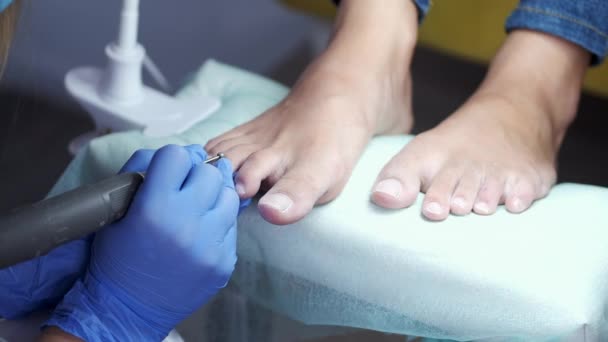 Мастер по педикюру удаляет кутикулу из ногтей на пальцах ног — стоковое видео