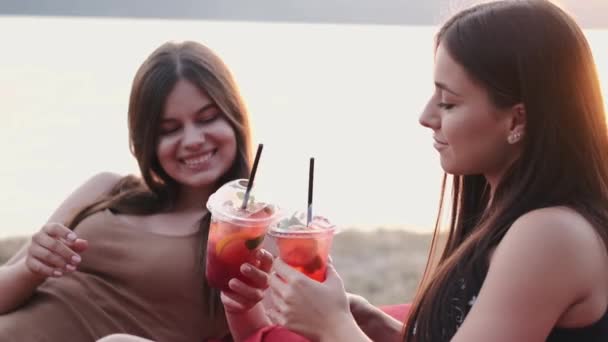 Två europeiska damer dricker drinkar på stranden — Stockvideo