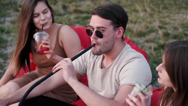 Mladý muž kouřící hadici a dámy se baví — Stock video