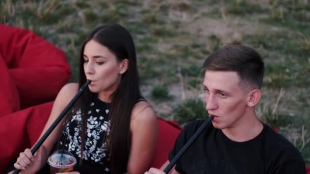 Die Freunde rauchen Shishas und sitzen am Strand — Stockvideo