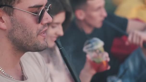 Dos chicos europeos están fumando y una chica está bebiendo un cóctel — Vídeo de stock