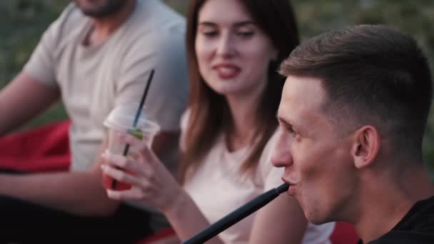 Két európai fiú dohányzik, és egy lány koktélt iszik. — Stock videók