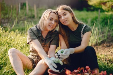 Mother with a daughter works in a garden near the house