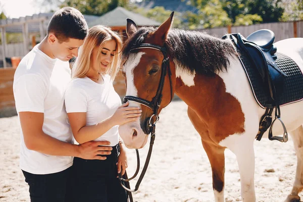 Beautiful couple spend time with a horses — Stock Photo, Image