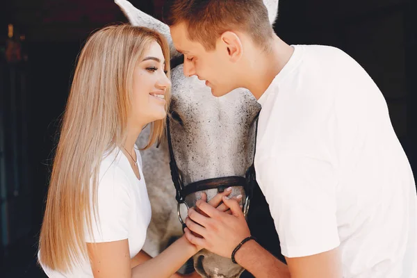 Beautiful couple spend time with a horses — Stock Photo, Image