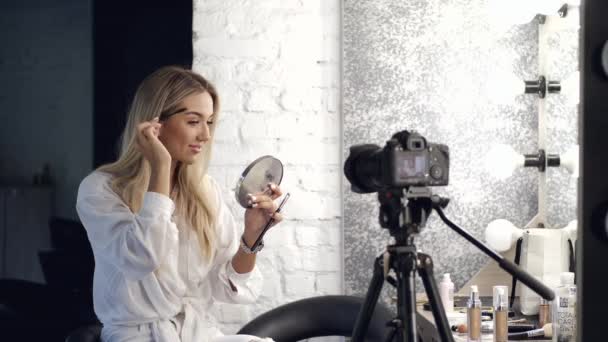 The pretty blond makeup artist is brushing eyebrows looking in a mirror — 비디오