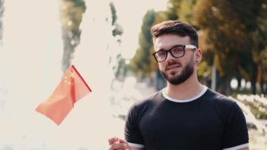 Genç adam Çin bayrağını bir çubukta gösteriyor.