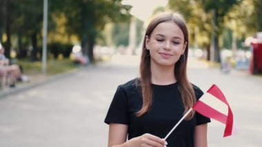 Bir kız öğrenci Avusturya bayrağını sallıyor.