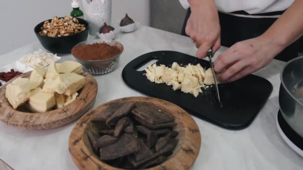 A mulher está cortando barra de chocolate em uma placa de corte — Vídeo de Stock