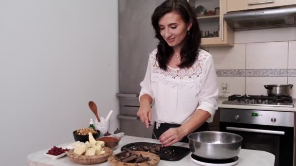 Europäische Hausfrau schneidet dunkle Schokolade in einer Küche — Stockvideo
