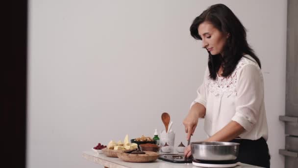Домохозяйка режет тёмный шоколад на доске — стоковое видео