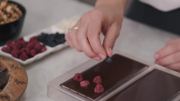 Hemmafrun dekorerar choklad i en form med bär — Stockvideo