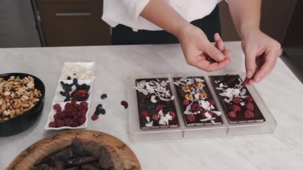 De huisvrouw versiert chocolade in een vorm met bessen en walnoten — Stockvideo