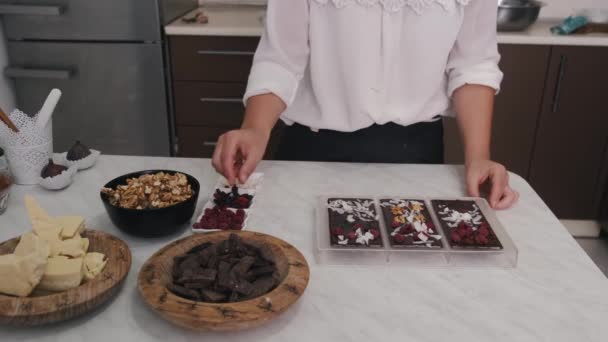 De huisvrouw versiert chocolade in een vorm met bessen en walnoten — Stockvideo