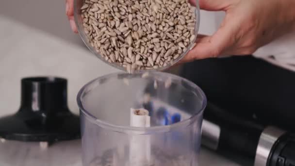 O cozinheiro está derramando sementes em uma tigela de liquidificador — Vídeo de Stock