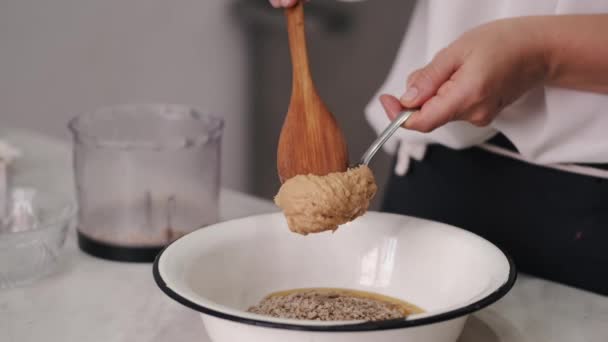 De chef voegt pindakaas toe aan de massa. — Stockvideo