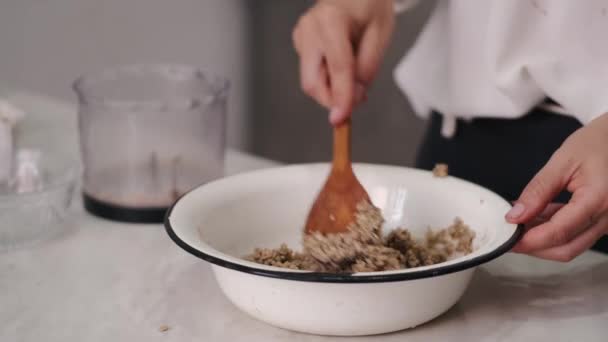 De kok roert de massa in een kom met een houten lepel — Stockvideo