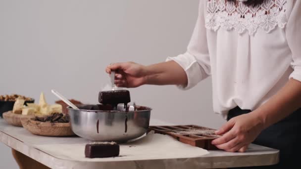 Een banketbakker dompelt een zoete in de gesmolten chocolade — Stockvideo